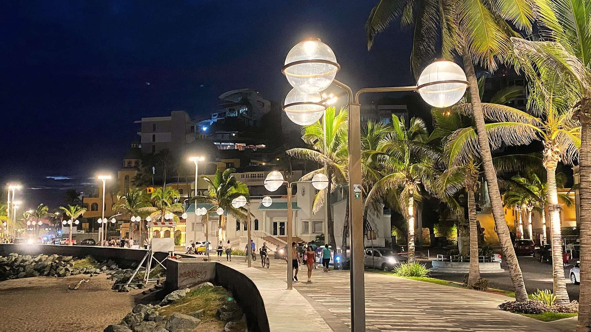 El malecón de Olas Altas de noche, con gente caminando, en el Centro Histórico de Mazatlán